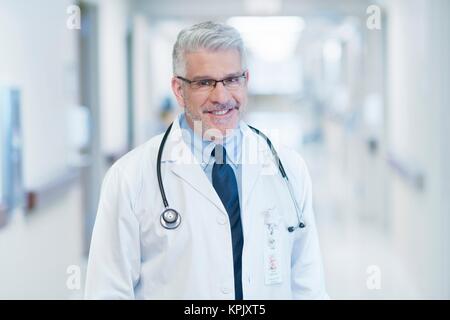 Reife männliche Doktor Brille, lächelnd in Richtung Kamera. Stockfoto
