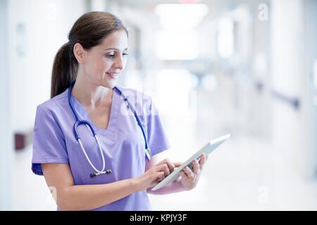 Krankenschwester trägt Lila einheitliche mit digitalen Tablet. Stockfoto