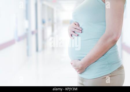 Schwangere Frau mit Hände auf Bauch, 7/8-Ansicht. Stockfoto