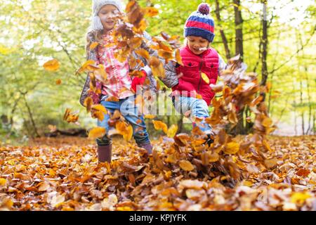 Kinder spielen in Blätter im Herbst. Stockfoto