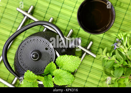 Tischplatte mit orientalische Teekanne und Schale mit frischen Kräutern Stockfoto