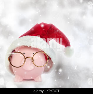 Sparschwein mit Weihnachtsmann Mütze und Brille in einem glitzernden Hintergrund Stockfoto