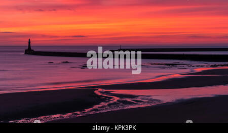 Silhouette einer Mole und Leuchtturm mit dramatischen und lebendigen sunrise Farben in den Himmel und spiegeln sich in den Ozean Wasser Stockfoto