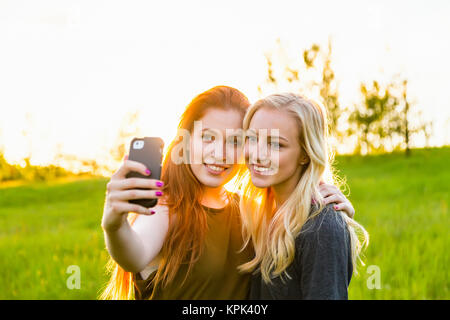 Zwei Freunde, die in einem Park, ein Selbstporträt mit einem Smart Phone in der Dämmerung; Edmonton, Alberta, Kanada Stockfoto