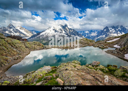 Lac Blanc spiegelt den Himmel, mit Mont Blanc Massiv und Refuge du Lac Blanc im Hintergrund; Chamonix-Mont-Blanc, Haute-Savoie, Frankreich Stockfoto