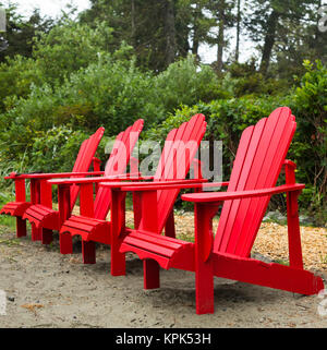 Vier rote Adirondack Stühle in einer Reihe auf Chesterman Beach, Vancouver Island, Pacific Rim; Tofino, Britisch-Kolumbien, Kanada Stockfoto