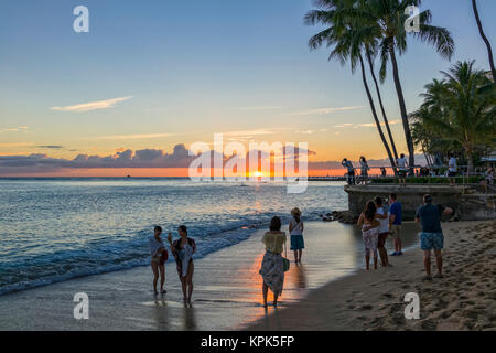 Touristen beobachten und fotografieren Sonnenuntergang am Strand von Waikiki, Honolulu, Oahu, Hawaii, Vereinigte Staaten von Amerika Stockfoto