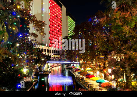 Die San Antonio Riverwalk gekleidet in it's Holiday Pracht mit Weihnachtsbaum leuchtet und festlichen Gebäude Lichter im dunklen Wasser widerspiegelt. Stockfoto