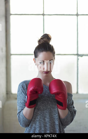 Ernsthafte junge Frau Boxhandschuh starrte Stockfoto