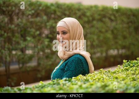 Schöne junge muslimische Frau mit Kopftuch weg schauen lächelnd im Freien Stockfoto