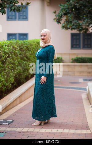 Schöne junge muslimische Frau mit grünen Kleid stehen im Freien Stockfoto