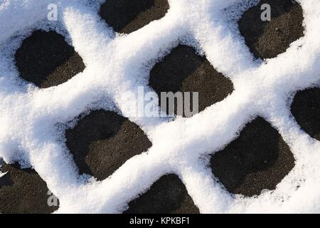 Schnee auf die Gelenke von Pflastersteinen einer Fußgängerzone im Winter Stockfoto