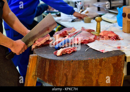 Metzger mit Cleaver bis Fleisch auf Metzger Block in Athen Zentrum Fleischmarkt, Griechenland schneiden Stockfoto