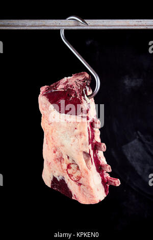 Einzelnen Stück roh geschlachtet Cote de boeuf Rindfleisch Rippen mit Fett Stück auf Haken hängen von Regal Stockfoto