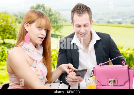 Junges Paar mit einem Smartphone in einem Café Terrasse Stockfoto