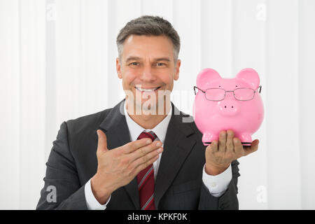 Reifen Geschäftsmann Holding Sparschwein im Büro Stockfoto