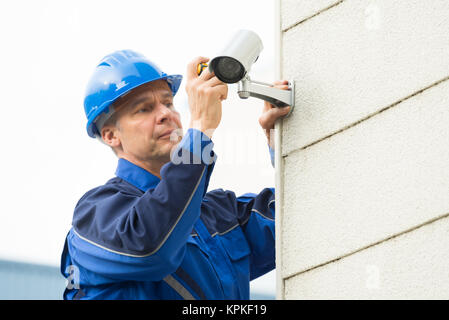 Männliche Techniker zur Festsetzung der CCTV-Kamera an der Wand Stockfoto