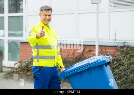 Der Mann hält Mülltonne auf der Straße Stockfoto
