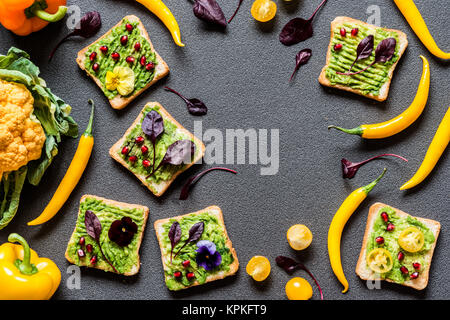 Frühstück verschiedenen avocado Sandwich. Verschiedene frische bunte Bio Gemüse. Gesunde Rohstoffe veganes Essen auf grauem Hintergrund. Stockfoto