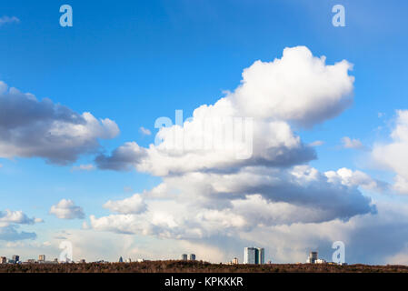 Große cumulus Wolken im Himmel über Häuser und Wald Stockfoto