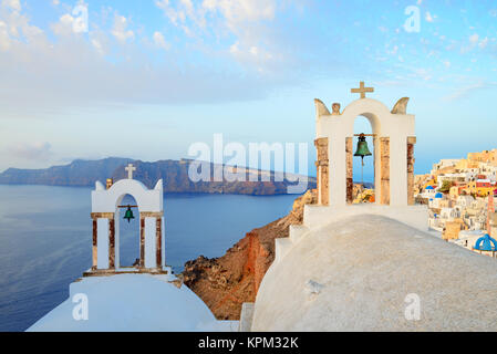 Blick auf das Dorf Oia auf Santorini über die Glockentürme der lokalen Kirche in den frühen Morgenstunden Stockfoto