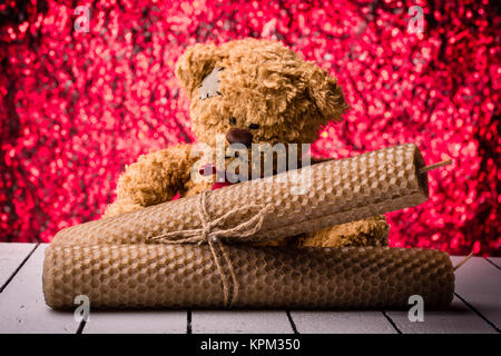 Kerzen aus Bienenwachs und Teddybär auf schönen roten Hintergrund bukeh Stockfoto