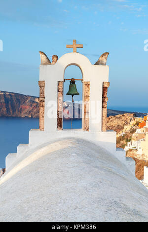 Blick auf das Dorf Oia auf Santorini über die Glockentürme der lokalen Kirche in den frühen Morgenstunden Stockfoto