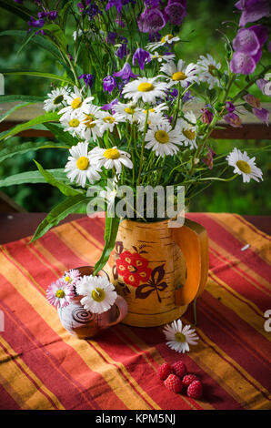 Ein Strauß Gänseblümchen in einen Krug am Tisch Stockfoto