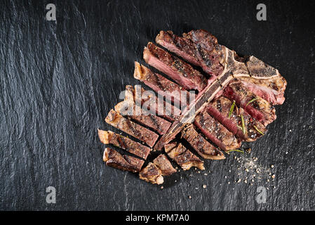 Gourmet gegrilltes Steak in Scheiben geschnitten und zu gewürzt mit Kräutern und Gewürzen und auf einer Schiefertafel Zähler serviert, hohe Betrachtungswinkel Stockfoto