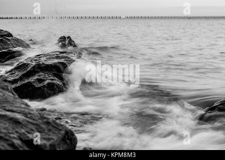 Wellen über die Felsen am Strand in Essex Stockfoto