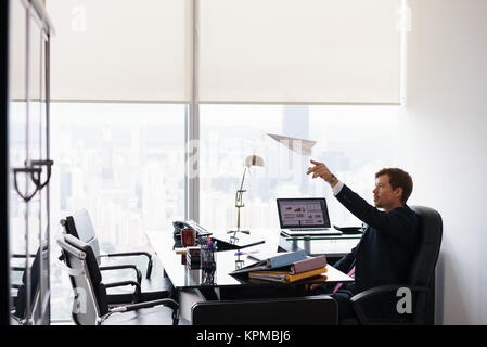 Erfolgreicher Mann Büroangestellter Tagträumen werfen Papierflieger Stockfoto