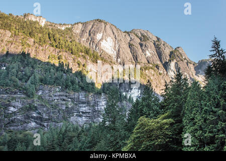 In Princess Louisa Inlet, Morgensonne leuchtet die Berggipfel entlang dem westlichen Ufer, während niedrigere Erhöhungen immer noch im Schatten (British Columbia). Stockfoto