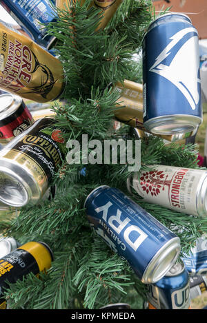 Kleine grüne künstlicher Weihnachtsbaum dekoriert mit leeren blau, gold, blau und weiß Bier und Apfelwein Dosen auf Meredith Music Festival. Stockfoto