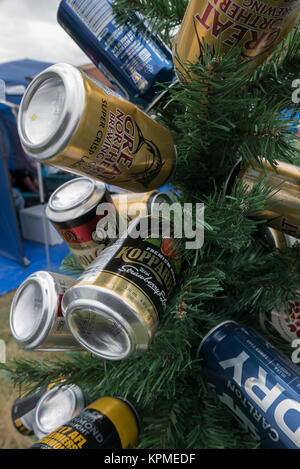 Kleine grüne künstlicher Weihnachtsbaum dekoriert mit leeren blau, gold, blau und weiß Bier und Apfelwein Dosen auf Meredith Music Festival. Stockfoto