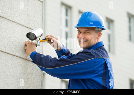 Reifen Techniker installieren die Kamera an der Wand mit einem Schraubendreher Stockfoto