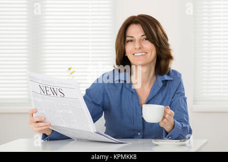 Frau mit Tasse und Zeitung Stockfoto