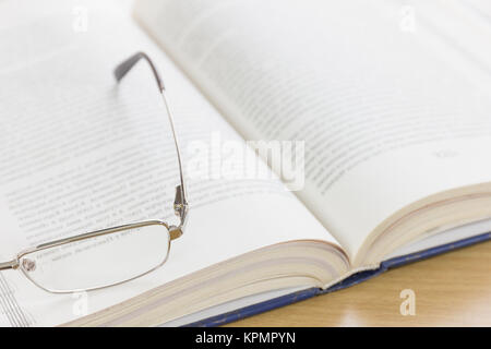 Close up Gläser und offenes Buch auf dem Schreibtisch Stockfoto