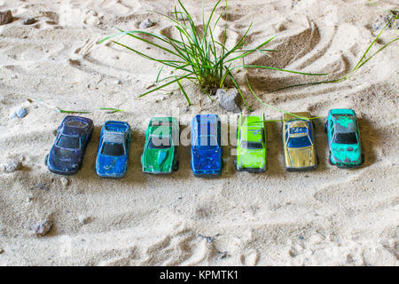 Rennwagen auf der Strecke oben in einer Reihe ausgerichtet. Ein Green Bush wächst von hinten. Wüste Stockfoto