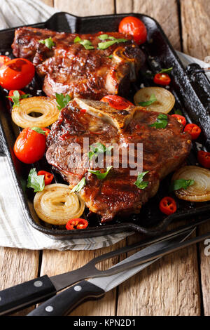 Leckeres barbecue: T-Bone Steak mit Tomaten, Paprika und Zwiebeln auf dem Grill Pfanne close-up auf dem Tisch. Vertikale Stockfoto