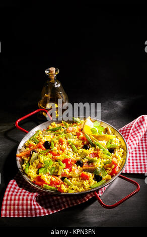 Köstliches Gericht von veggie verduras Paella mit grünem Spargel, Paprika und Oliven in einem Bett von gelben Safranreis auf einer rot-weißen rustikalen Serviette mit Kopie Raum Stockfoto