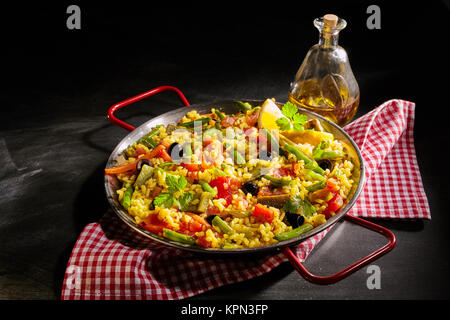 Gesunde Portion Paella verduras mit Spargel im Traditionellen Spanischen vegetarische Rezepte mit Paprika, Kräutern und Oliven auf einem Bett von gelben Safranreis mit einem Olivenöl Dressing serviert. Stockfoto