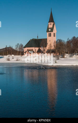 Kirche mit hölzernen schin Knödel vor dem Brunnen in Arjeplog - Lappland am Ufer des sÃ¤lla auftauen und die Kirche im See spiegeln, der Kirchturm mit Blick nach Osten. Stockfoto