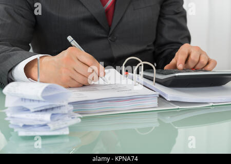 Geschäftsmann Berechnung der Steuer im Büro Schreibtisch Stockfoto