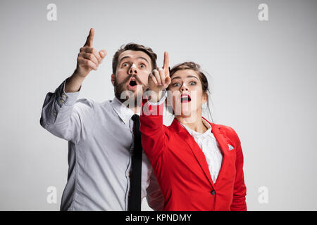 Die überraschten business Mann und Frau auf einem grauen Hintergrund Stockfoto