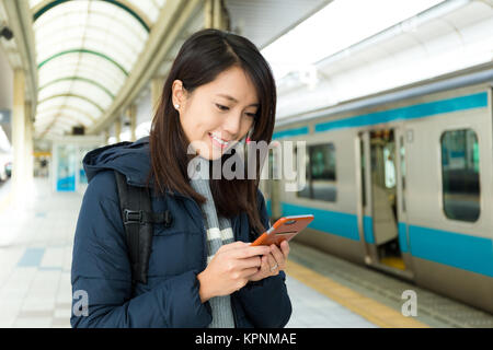 Frau Verwendung von Handys in Zügen station Stockfoto