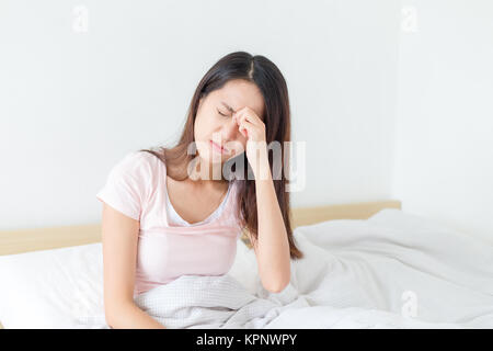 Frau leiden unter headahce und sitzen auf dem Bett Stockfoto