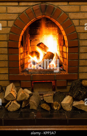 Stapel von Holz und Zungen aus Feuer in indoor gemauerten Kamin im