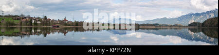 Nord-östlichen Panorama-Ansicht über den Weissensee nahe der Stadt Füssen im Ostalgäu mit schöner Wasserspiegelung und der Ortschaft Weissensee sowie schneebedeckten Bergen im Hintergrund Stockfoto