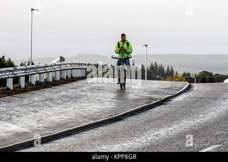 Radfahrer mit Handy während Radfahren auf der Fahrbahn/Gehweg Stockfoto