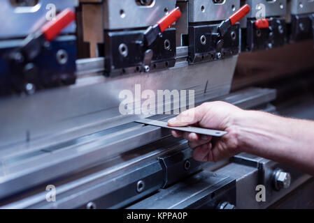 Der Arbeitnehmer mit der rechten Hand eine Metallplatte Stockfoto
